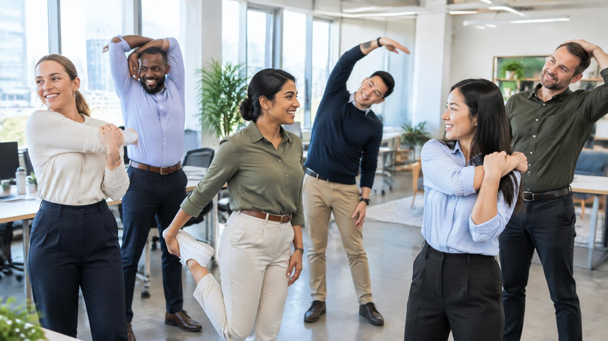 Diverse team of office workers doing a stretching break in a bright modern office